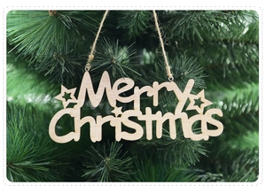 Detail of laser-cut wooden Merry Christmas ornament hanging on a festive tree branch