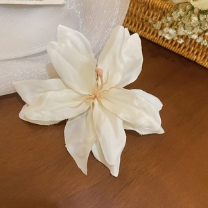 Pince à cheveux lys blanc en tissu avec pistils roses sur une table en bois