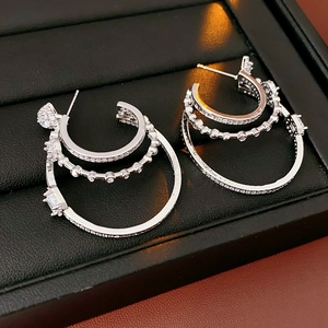 Detailed close-up of triple-layered silver earrings with sparkling cubic zirconia inlay