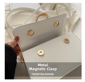 Detail of white leather bag with two golden circular magnetic snap buttons and shoulder strap