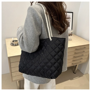 Gros plan du sac fourre-tout noir matelassé avec poignées en corde blanche sur modèle