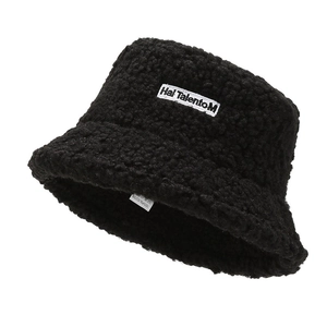Detail of black fluffy winter bucket hat showing sheepskin texture and square logo patch