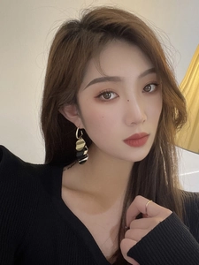Close-up of model wearing retro gold and black geometric tassel earrings and a thin gold ring