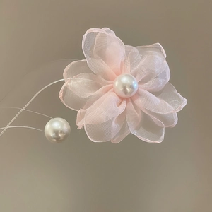 Macro detail of delicate pink chiffon flower earring with elegant pearl embellishments