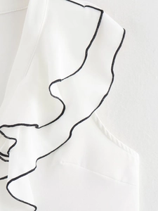 Detail of white ruffled top with black contrast trim showing neckline and sleeve craft