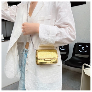 Model wearing a gold crocodile pattern mini crossbody bag with a silver chain strap
