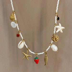 Macro detail of beaded necklace with gold starfish, strawberry, and pearl charms