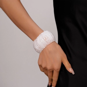 Détail macro d'un large bracelet en résine acrylique blanche avec motif géométrique