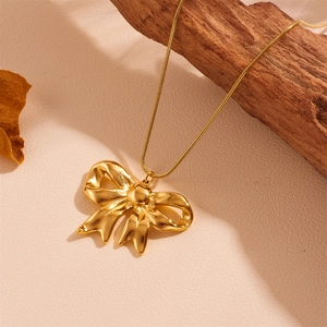 Titanium steel gold bowknot necklace on a natural wood background for a chic look