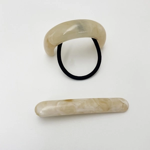 Detailed set of beige marble resin hair tie and matching clip on white background