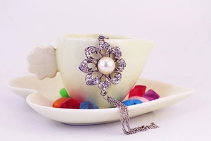 Close-up of silver flower pendant with crystals, large pearl and metal chain tassels