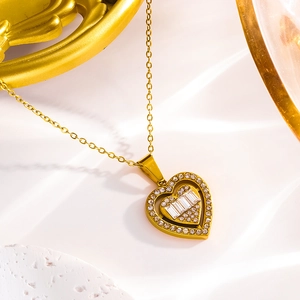 Collier luxueux avec pendentif cœur doré orné de zircons sur un fond de pierre blanche