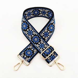 Close-up of ethnic floral embroidery on a wide adjustable shoulder strap with gold clips