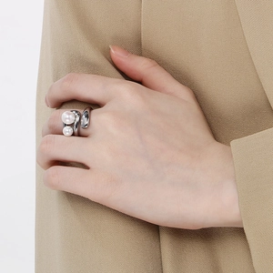 Detail of silver double-loop pearl ring worn against a chic khaki blazer background