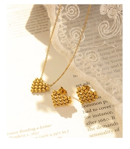 Macro detail of gold beaded heart necklace and earrings on vintage book with lace