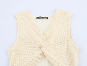 Detail eines beigen Strickkleides mit V-Ausschnitt und Knotendesign auf Netzstoff