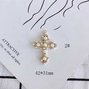 Detail of a golden heart cross pendant with pearls and rhinestones measuring 42x31mm