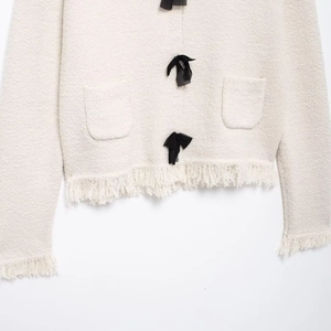 Elegant knit cardigan in cream white with black bow details and stylish fringe trim