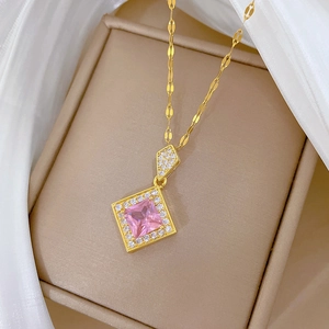 Macro detail of a gold rhombus necklace with a pink square gem in a brown jewelry box