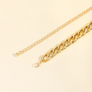 Close-up of gold metal waist chain belt with lobster clasp and bead charm detail