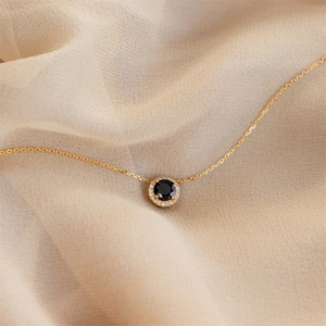 Detail showing halo pendant with black gemstone and white diamonds on gold chain