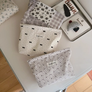 Three floral and checkered cotton makeup bags with simple wish labels on beige surface