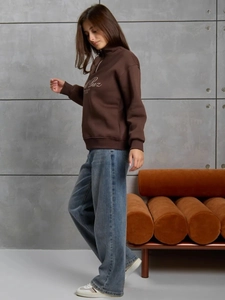 Vue latérale d'une femme portant un sweat marron demi-zip et un jean bleu large