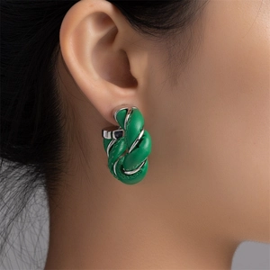 Close-up of green twisted leather hoop earring worn by a model with metallic details