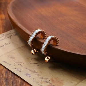 Gold C-shaped stud earrings with square zircon crystals on a vintage background
