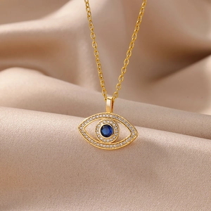 Detail of golden Evil Eye necklace with blue stone and white crystals on silk