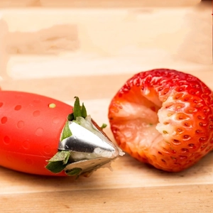 Close-up of stainless steel strawberry huller removing stem from fresh fruit