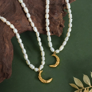 Chic freshwater pearl necklace with gold crescent moon pendants on a vintage wood backdrop