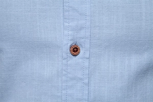 Macro du tissu en lin bleu clair avec un bouton en bois marron et gravure fashion
