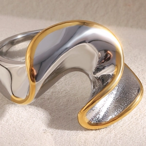 Vue macro d'une bague en acier doré 18K bicolore au design fluide et torsadé unique