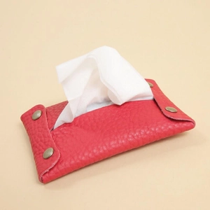 Detail of red leather tissue pouch with a metallic snap button for portable tissue storage