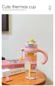 Roze rietjesbeker met handvatten, citroenschijfjes en zonnebloembedeltje op houten tafel