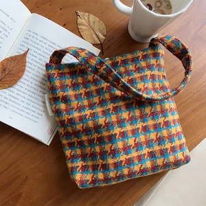 Close-up of retro knit shoulder bag texture with red yellow and blue plaid on a wooden desk