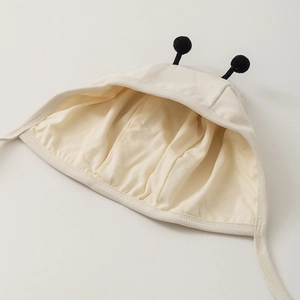 Detail of baby bee bonnet showing off-white cotton fabric and plush black antennae