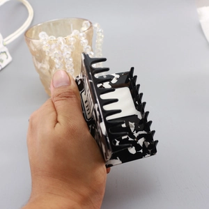 Detail of large square hair claw clip featuring black and white marble pattern design