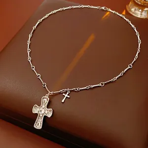 Silver-toned double cross pendant necklace with crystal pavé on dark leather background