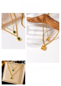Close-up of gold double-layer chain necklace with green square gemstone pendants