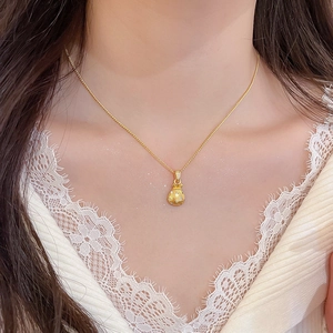 Close-up of golden lucky bag pendant with sparkling zircons on a delicate chain necklace