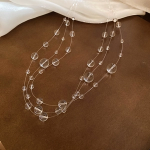 Detailed close-up of triple-layered irregular clear crystal beads on silk fabric