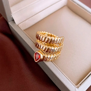 Detail of a vintage-style gold-plated snake ring with a red teardrop zircon gemstone
