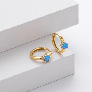 Polished gold hoop earrings featuring round blue opal stones on minimalist background