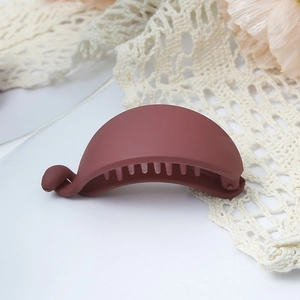 Detail view of a matte dark red banana hair clip with internal teeth on lace background