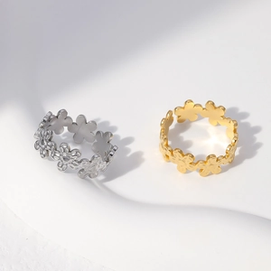 Detailed view of silver and gold daisy floral rings on a white textured background