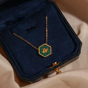 Gold bee pendant necklace with green malachite on silk background in velvet box