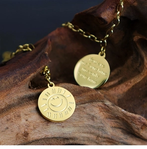 Detail of gold sunshine smile pendant with You are my Sunshine engraving on dark wood