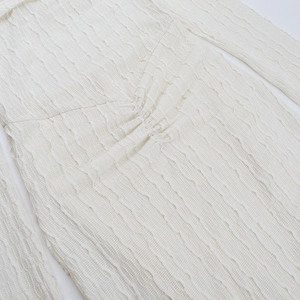 Détail du tissu à texture ondulée blanche avec couture froncée centrale et tricot